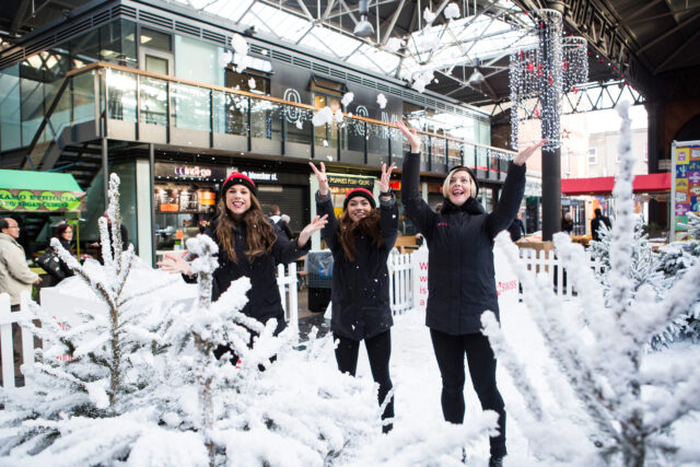 People in wintry gear throw snow in the air