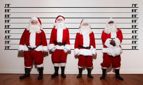 Four Santas line up against a wall