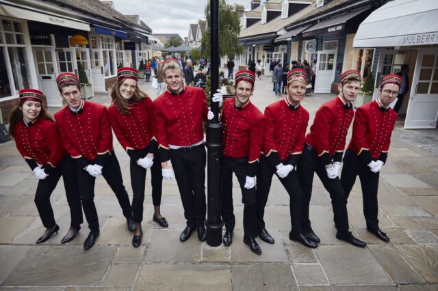 Bellboys pose around a lamppost