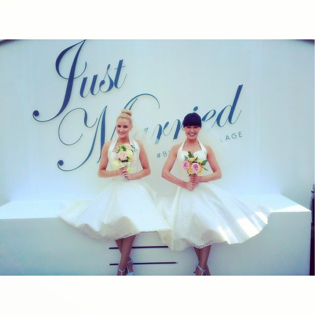 two brides pose I front of a just married sign