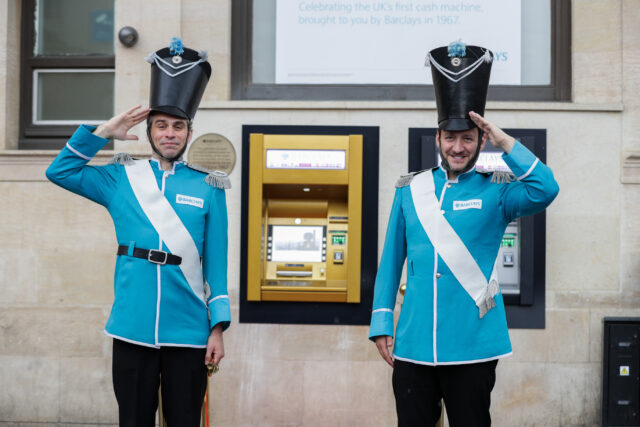 two guards salute either side of the golden cash machine