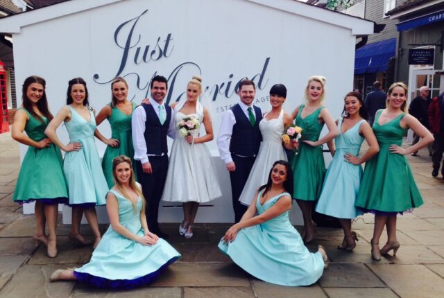 The bridal party poses in front of a just Married sign