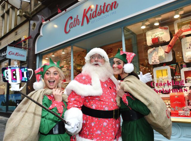 Santa and his elves take selfie in front of a Cath Kdston store