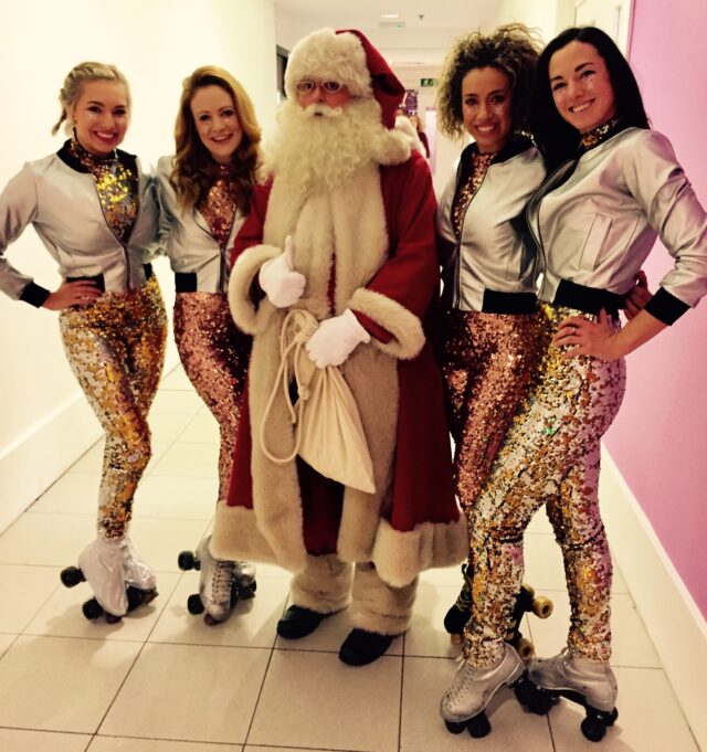 Dancers in shiny gold leggings pose with Santa