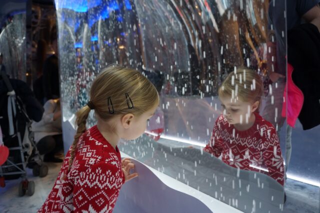 A girl in a red jumper looks at the snowy effect